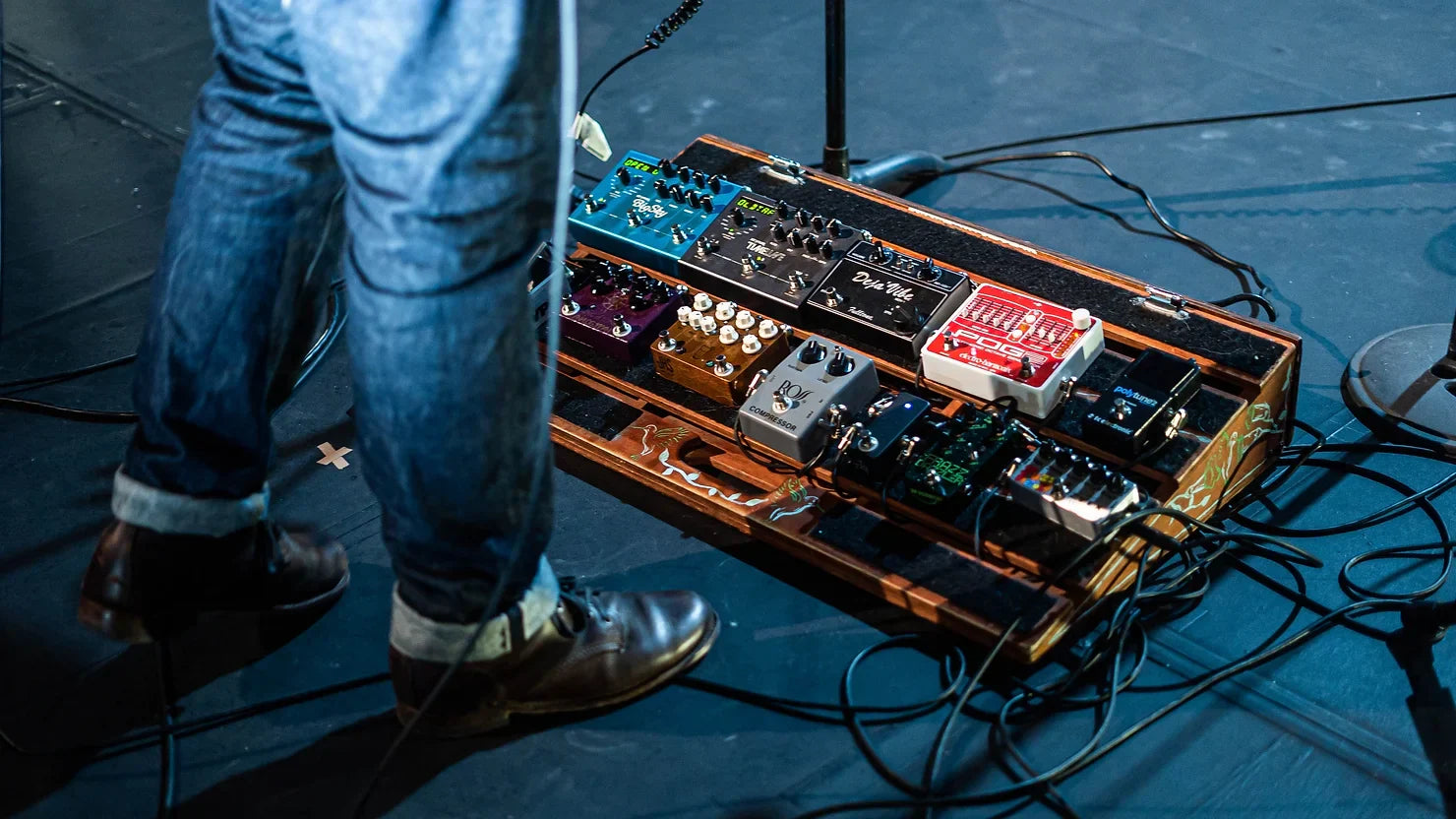 guitar pedalboard on stage with a musicians foot