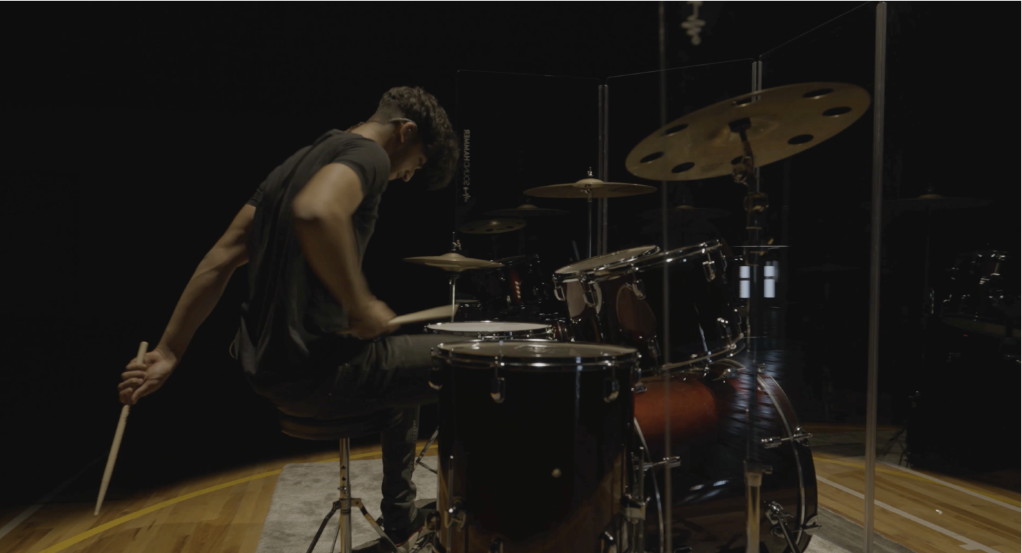 side view of a drummer playing drums with soundhammer drum kit drum-shield panels.