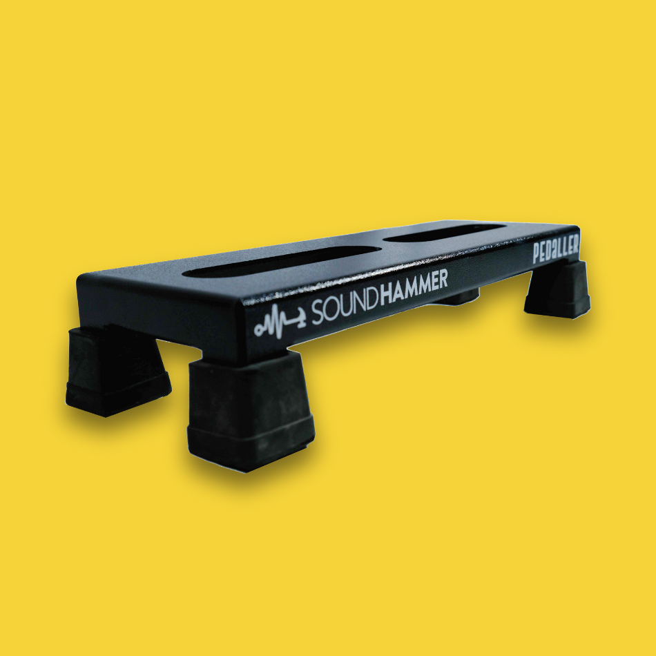 An angled view of a lifted black guitar effects pedalboard made of single sheet of aluminium with 4 legs and rubber bushings with Soundhammer logo.