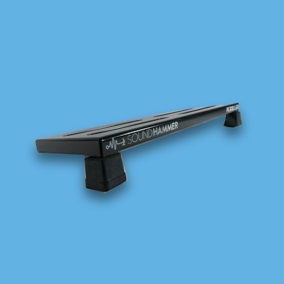 A top angled view of a long incline black guitar effects pedalboard made of single sheet of aluminium with 2 legs and rubber bushings with Soundhammer logo.