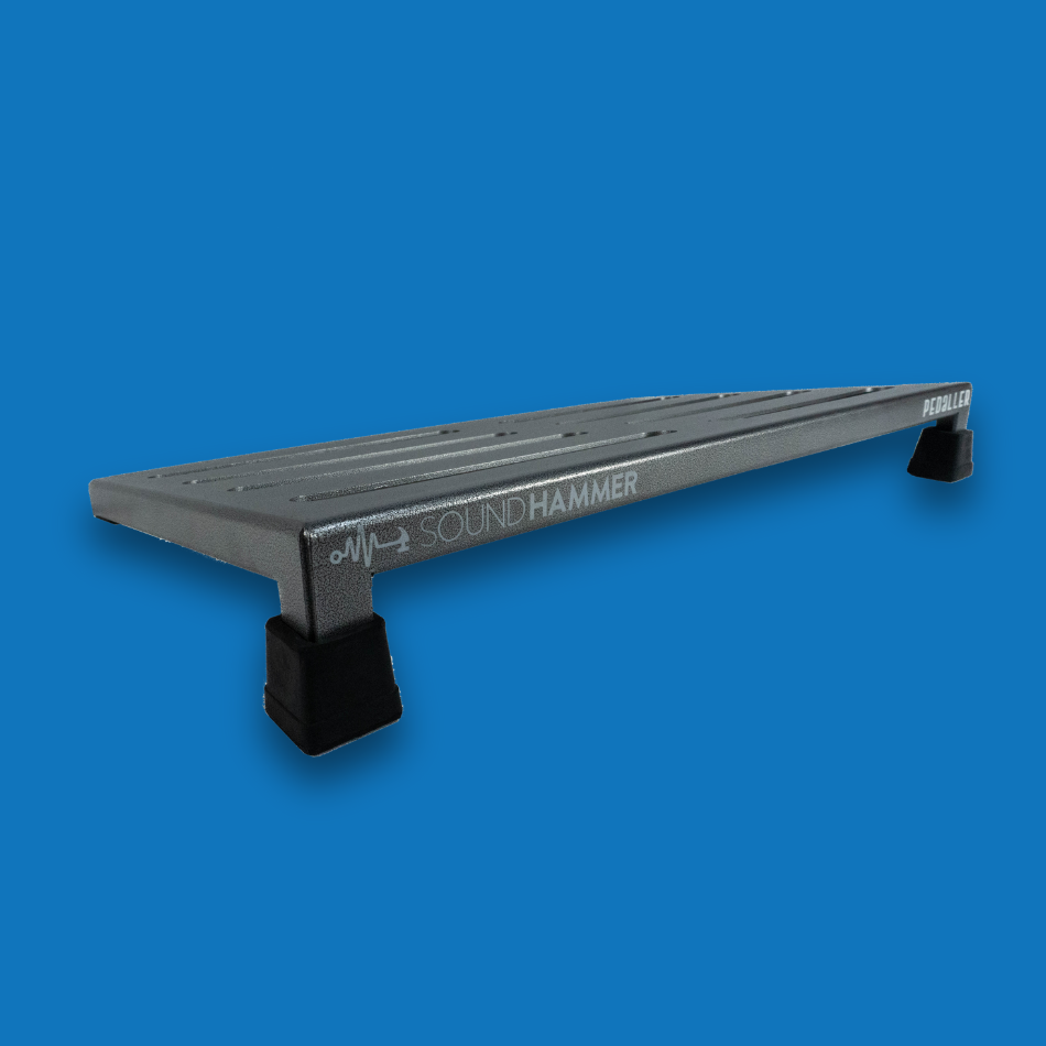 A top angled view of a large incline grey guitar effects pedalboard made of single sheet of aluminium with 2 legs and rubber bushings with Soundhammer logo.