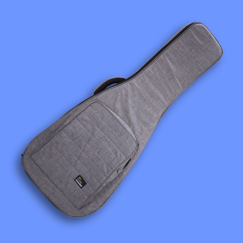A tilted view of grey guitar bag for acoustic guitar with front pouch & carry handle.
